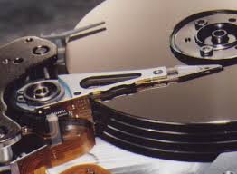A closeup image of the actuator arm and head and the hard drive platters.